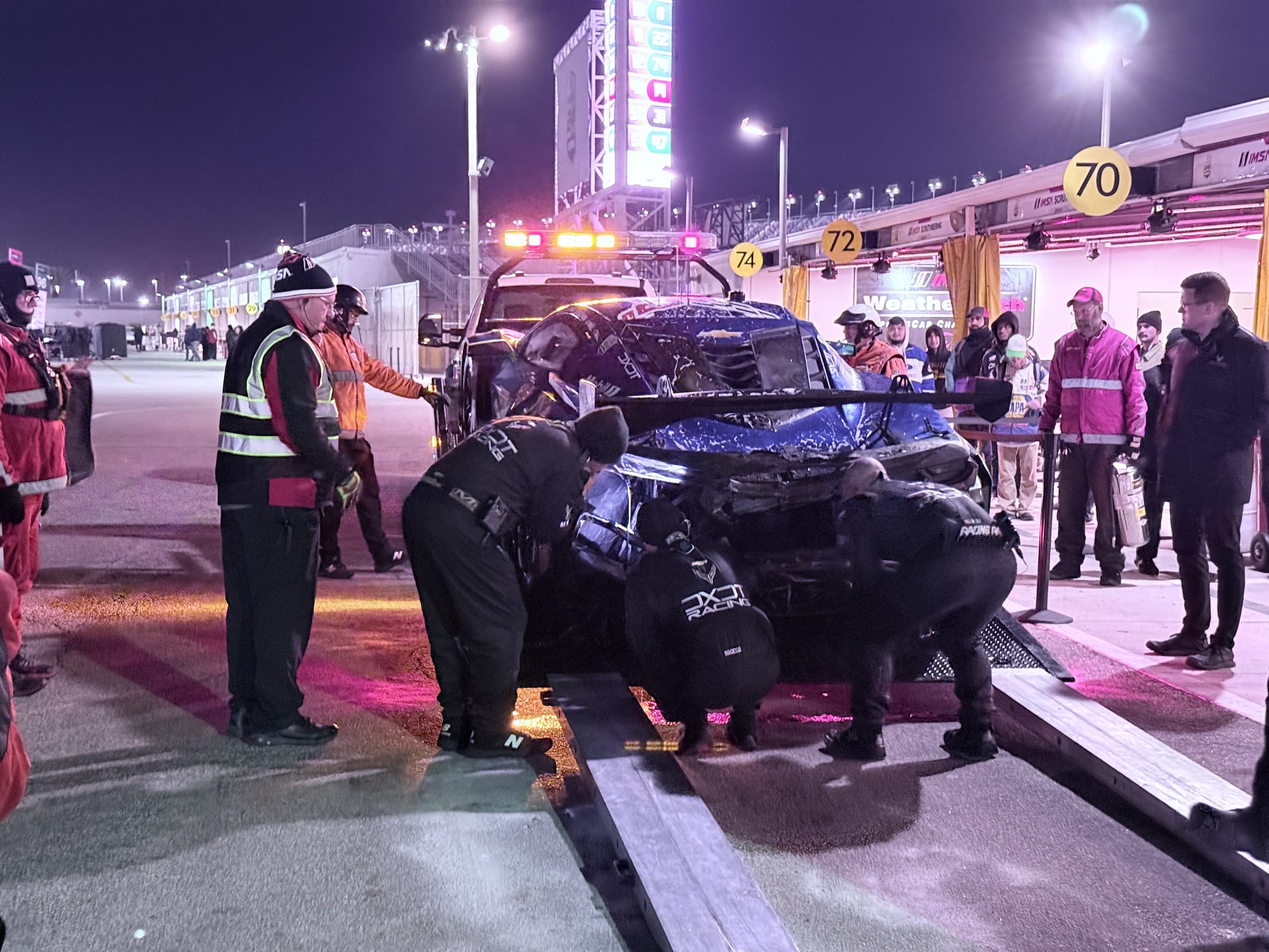 Crews recovering a completely burned up Corvette GT3 in front of its garage